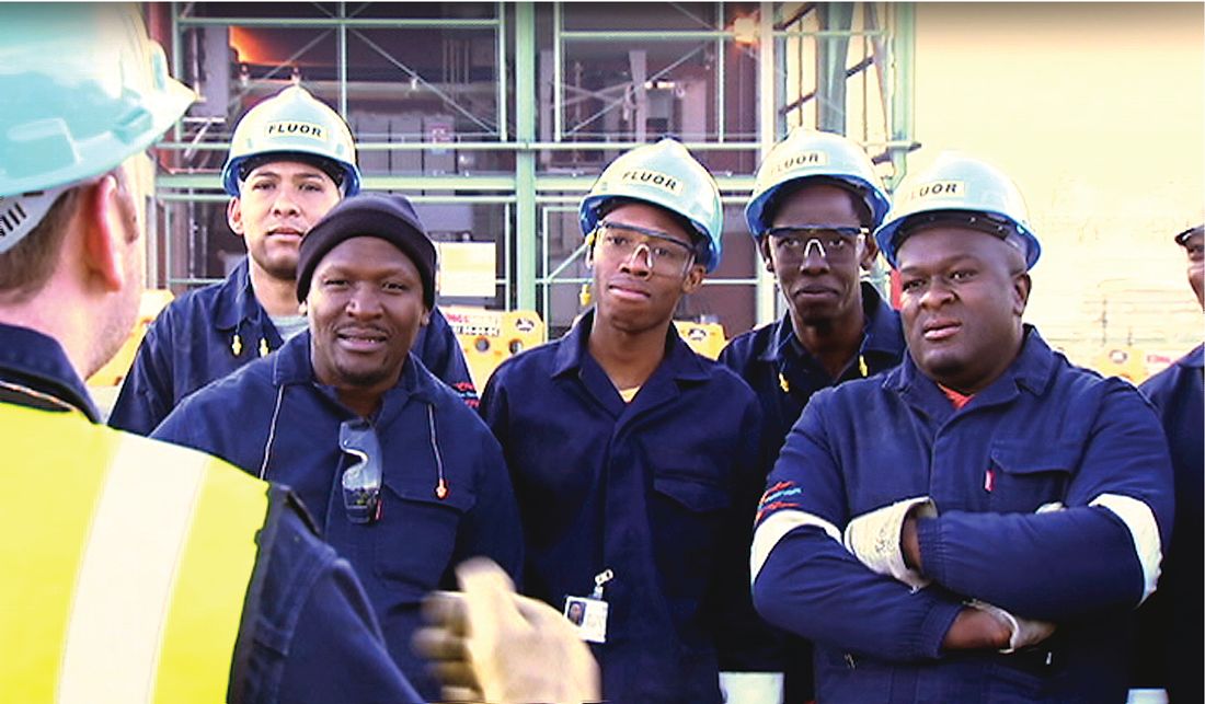 A group of workers in overalls and hard hats standing together on site