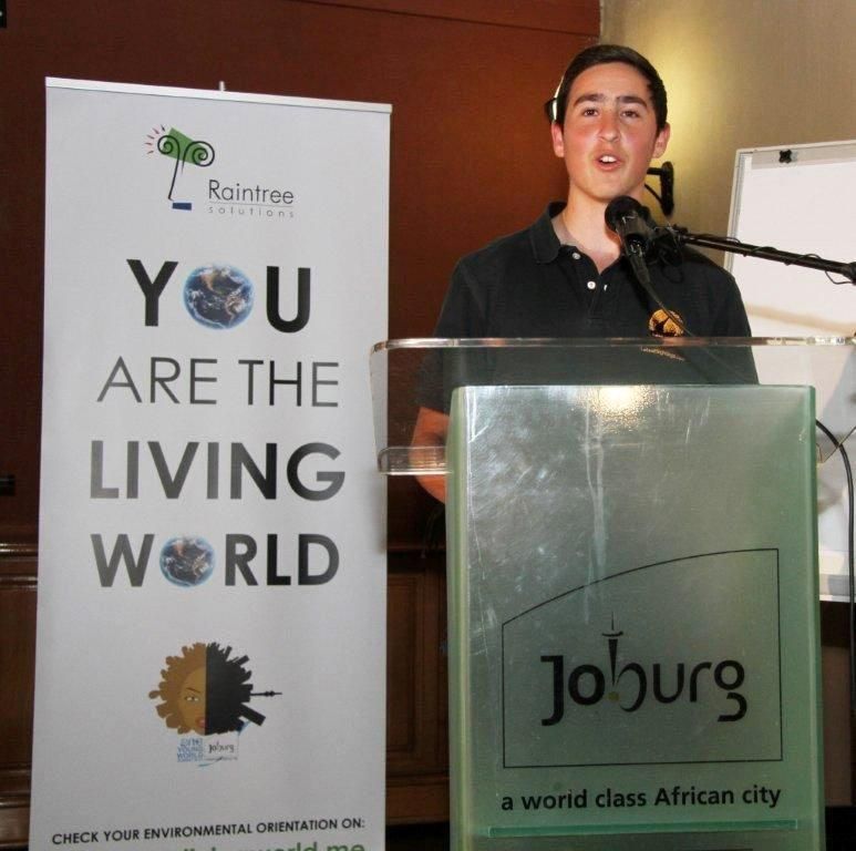 A presenter at a lectern beside a banner reading You are the living world