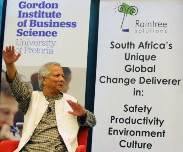 A speaker addressing the audience beside Gordon Institute of Business Science and Raintree banners