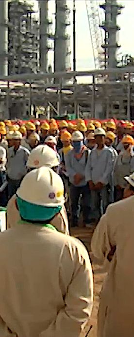Hundreds of workers in hard hats gathered for a safety talk at a refinery