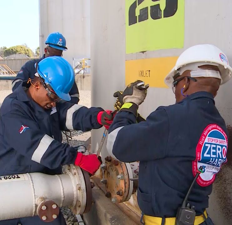 Two workers in hard hats checking equipment at an industrial plant