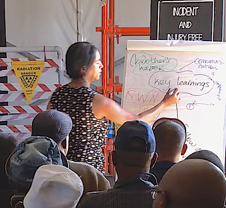 A facilitator presenting at a flip chart to seated workers